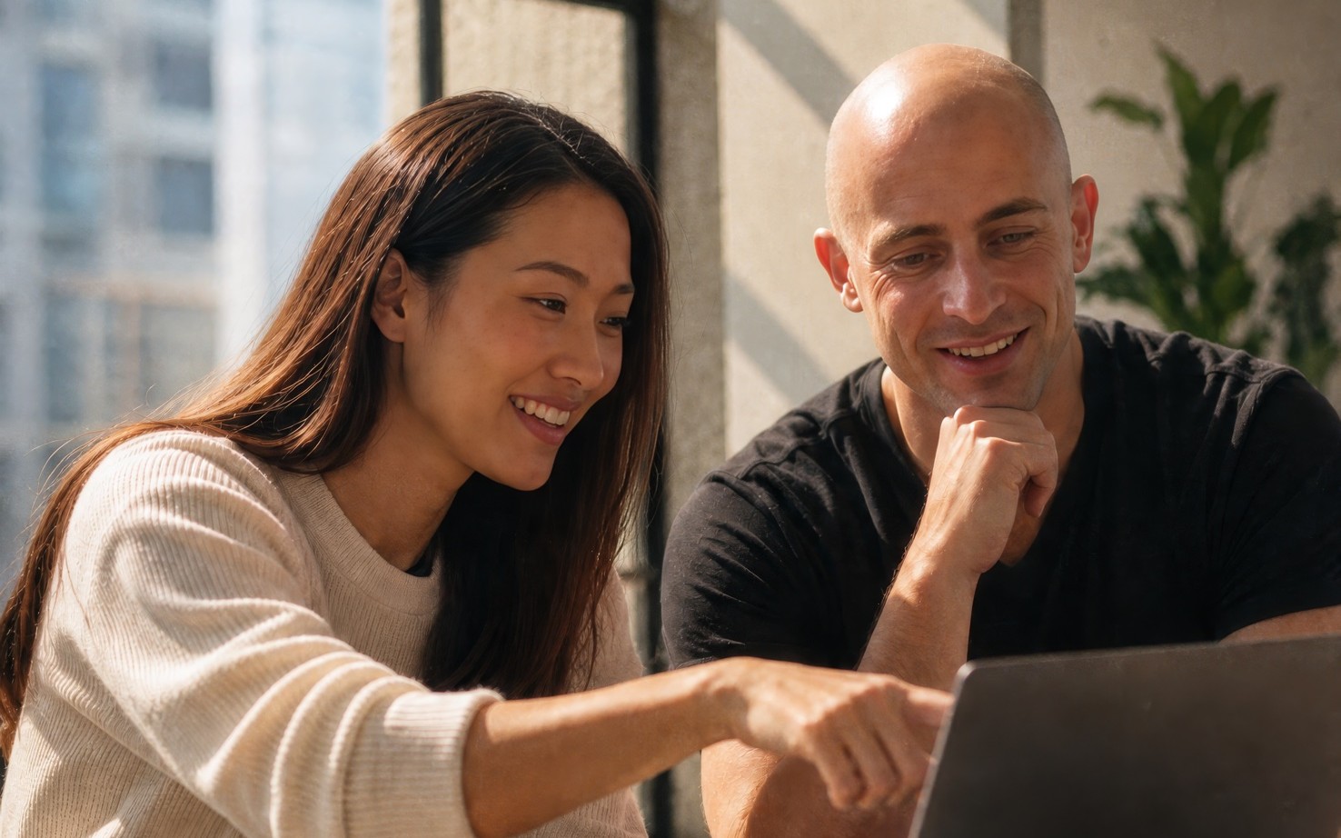 Two teammates working with AI on a laptop